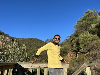 Portrait of young man sitting on steps against clear blue sky