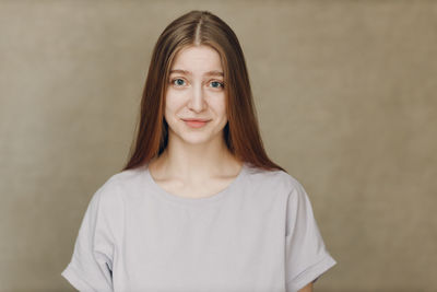 Portrait of young woman standing against wall