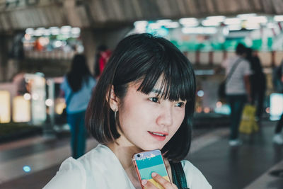 Close-up of thoughtful young woman holding phone