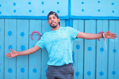 Smiling young man standing against blue wall