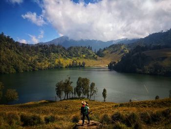 Man standing by lake against sky