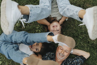 Directly above view of senior man with granddaughters lying on grass