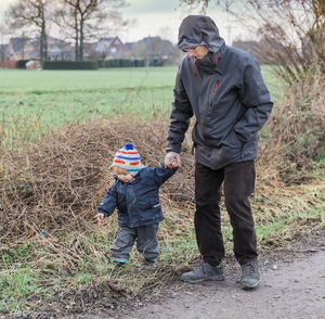 Grandfather and son walking on dirt road