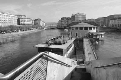 Bridge over river amidst buildings in city against sky