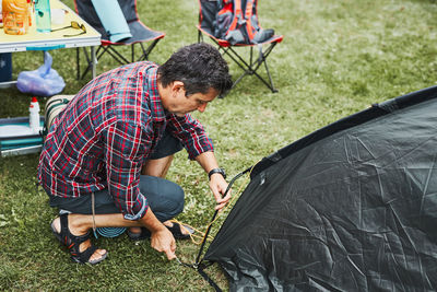 Man putting up a tent at camping during summer vacation. preparing campsite to rest and relax