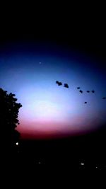 Low angle view of silhouette birds flying against sky at sunset