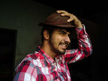 Man wearing hat looking away against old house 