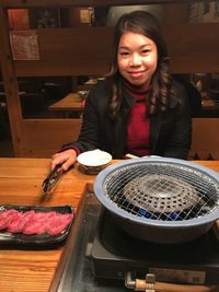 Portrait of smiling woman with barbecue grill on table at restaurant