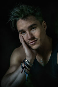 Close-up portrait of shirtless man against black background