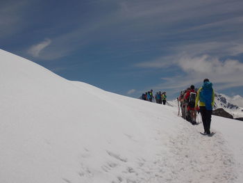 Rear view of people walking on snowcapped mountain