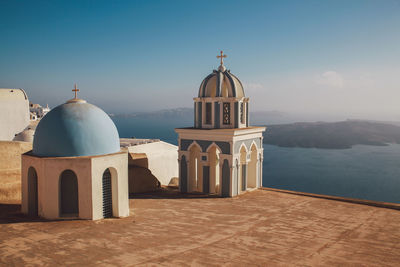 Church by sea against sky on sunny day