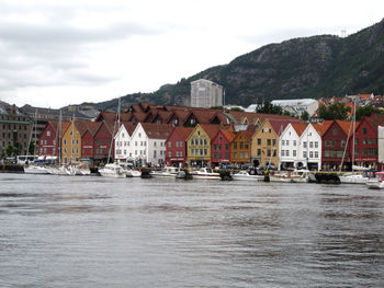 Buildings by river in town against sky