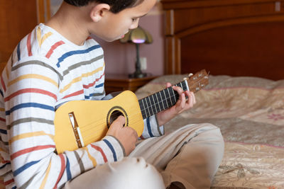 Midsection of man playing guitar at home