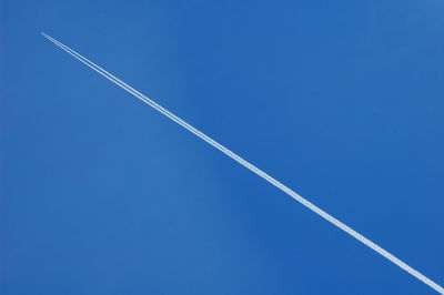 Low angle view of vapor trail against blue sky