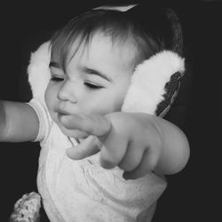 Close-up of cute girl holding cat against black background