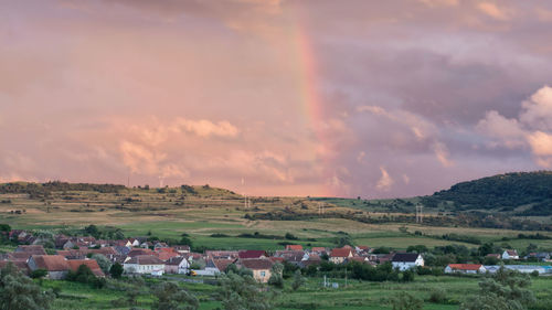 Houses on field against sky during sunset