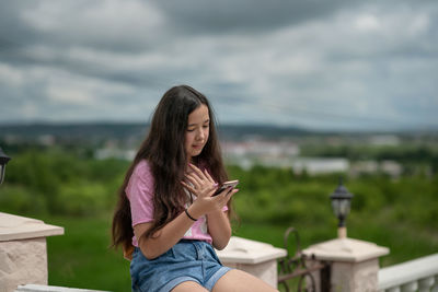 Portrait of young woman looking away against sky