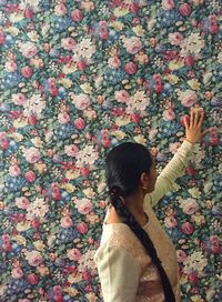 Woman touching floral pattern wall