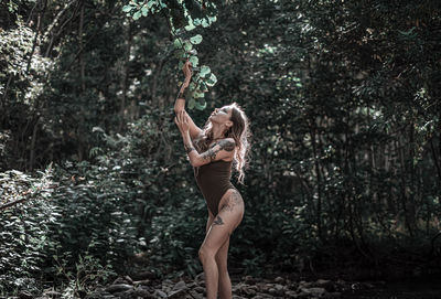 Midsection of woman standing by plants in forest