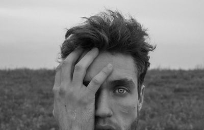 Close-up portrait of man wearing mask against sky