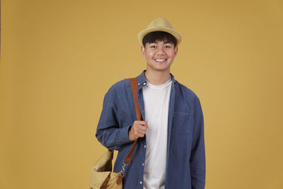 Portrait of smiling man standing against yellow background