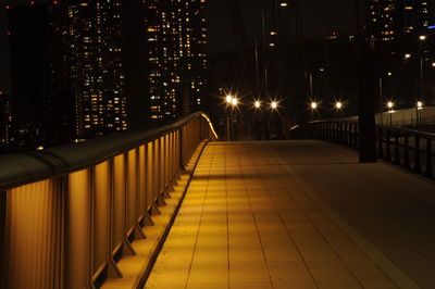 Illuminated footpath amidst buildings in city at night