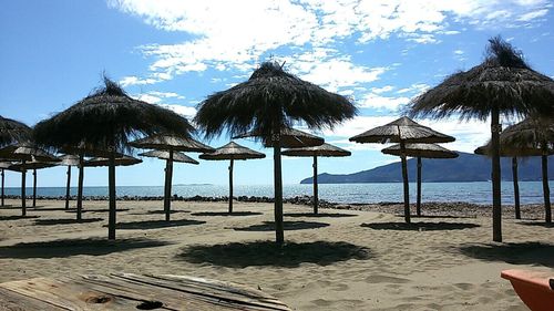 Deck chairs on beach against sky