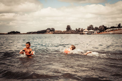 Little boys enjoying in summer day while swimming in the water.