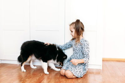 Woman with cat on hardwood floor against white background