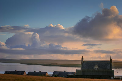 Houses by sea against sky during sunset