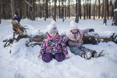 Full length of girl sitting on snow covered land