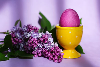 A bright purple easter egg and lilac flowers on a purple background. easter decor.