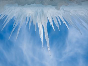 Low angle view of icicles against cloudy sky