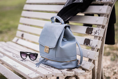 High angle view of purse with sunglasses and leather jacket on bench