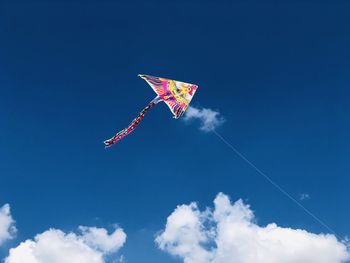 Low angle view of kite flying against blue sky