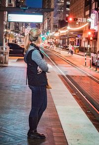 Rear view of woman standing in illuminated city at night