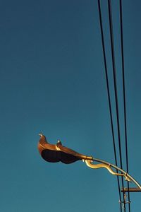 Low angle view of crane against clear blue sky