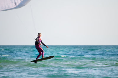 Young caucasian woman athlete ride on a hydrofoil board with a kite in the open ocean. hydrofoil is