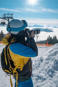 Rear view of man photographing on snow