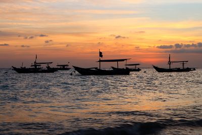 Silhouette boats in sea against sky during sunset