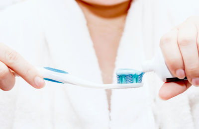 Midsection of woman putting toothpaste on brush