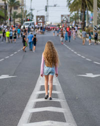 Rear view of girl walking on city street