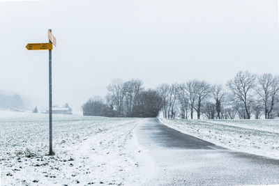 Road amidst snow covered trees against clear sky