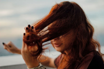 Close-up of young woman with hand in brown hair