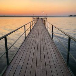 Pier over sea against sky during sunset