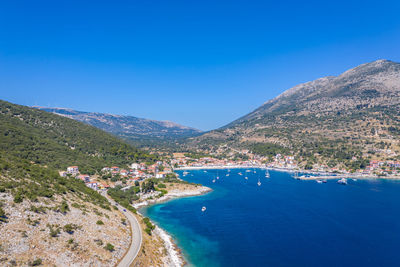 Scenic view of sea and mountains against clear blue sky