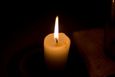 Close-up of lit candle in darkroom