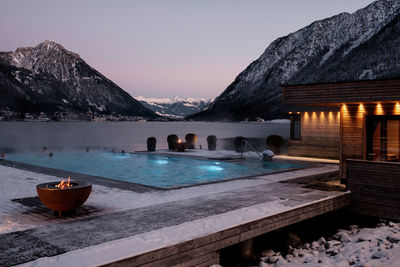 Scenic view of lake by mountains against sky at sunset