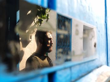 Young man looking away against window