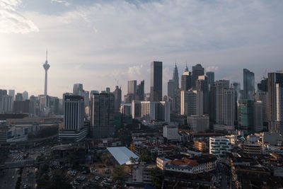 Aerial view of buildings in city against cloudy sky